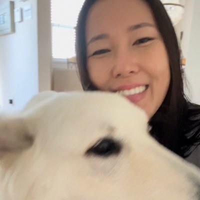 A woman smiles as she pets a white dog