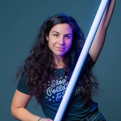 A woman is holding a neon light and posing for a picture