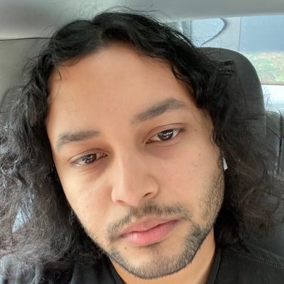 A man sitting in a car wearing a black shirt